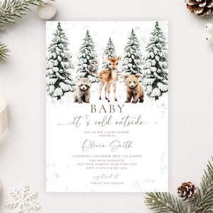 May include: A rectangular baby shower invitation card featuring a winter forest scene with snow-covered pine trees, a fawn, a bear cub, and a raccoon. The text reads: Baby it's cold outside, honoring Olivia Smith, Saturday December 18th at 4:00PM.