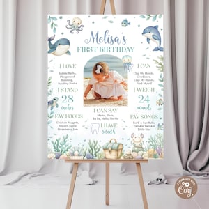 May include: A personalized first birthday sign with an under-the-sea theme. The sign features a photo of a baby, along with details like height (28 inches) and weight (24 pounds). Decorative elements include sea creatures and text.