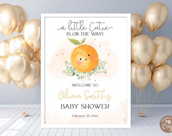 Puede incluir: Un cartel blanco con un fondo color melocotón y una naranja de dibujos animados con una cara sonriente. El texto en el cartel dice "a little Cutie is on the way!" y "Welcome to Olivia Smiths Baby Shower February 20, 20xx".