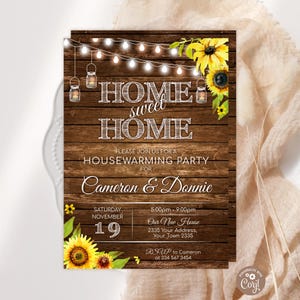 May include: A housewarming party invitation on a dark wood background featuring string lights, hanging mason jar lanterns, and yellow sunflowers. The text reads HOME sweet HOME, PLEASE JOIN US FOR A HOUSEWARMING PARTY, Cameron & Donnie, and event details.