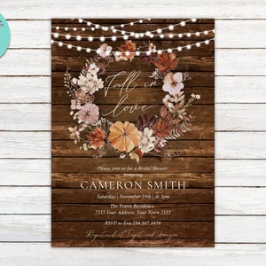 May include: Fall-themed bridal shower invitation with a rustic wood background. The invitation features a wreath of fall leaves and flowers with the text "Fall in love" in a handwritten font. The invitation also includes the bride's name, the date and time of the shower, the location, and RSVP information.