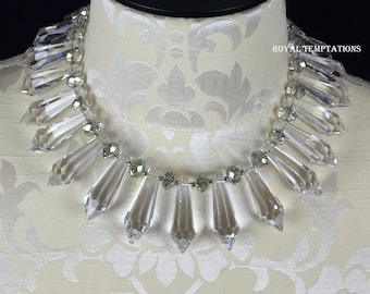 May include: A crystal necklace with clear teardrop-shaped beads and smaller silver beads. The necklace is on a white mannequin bust.