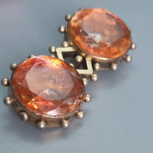 May include: A vintage brooch with two large, faceted, orange-brown gemstones set in silver.