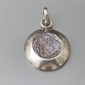 May include: A silver pendant with a round iridescent abalone shell inlay.
