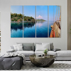 May include: A panoramic view of a blue body of water with a green island in the distance. A white sailboat is docked on the right side of the image.