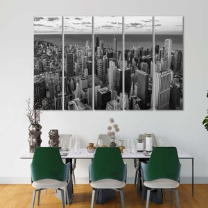 May include: Black and white panoramic photograph of a city skyline. The image is split into six panels, showing a cityscape with tall buildings and a river in the distance.