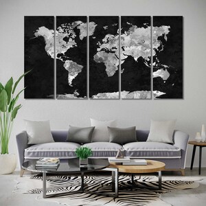 May include: A black and white world map canvas print in a modern living room setting. The print is divided into five panels and features a distressed, textured look. The map is displayed above a grey sofa with white and grey cushions. A zebra print rug is on the floor in front of the sofa.