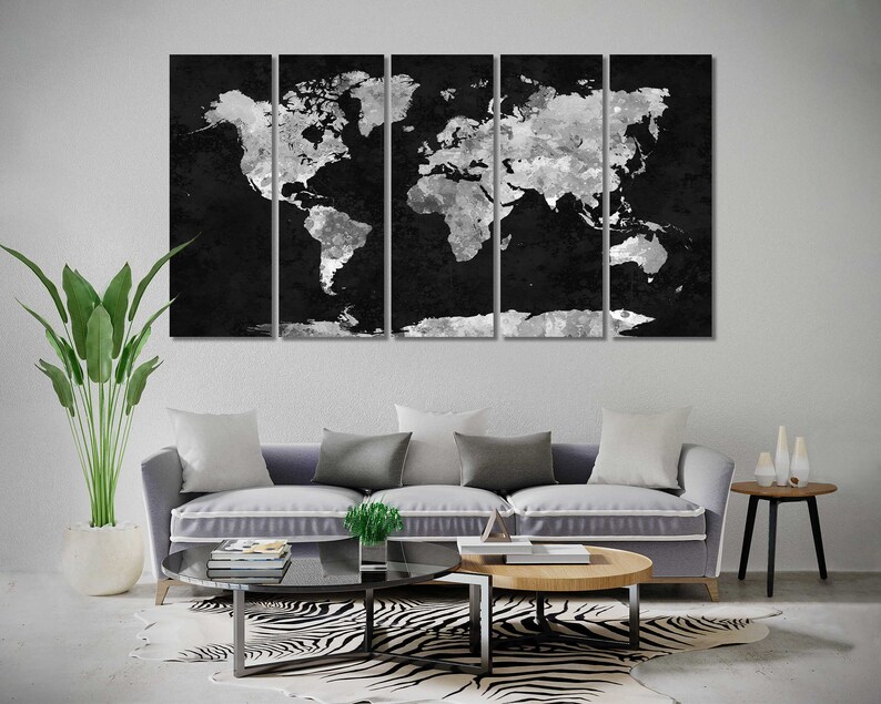 May include: A black and white world map canvas print in a modern living room setting. The print is divided into five panels and features a distressed, textured look. The map is displayed above a grey sofa with white and grey cushions. A zebra print rug is on the floor in front of the sofa.