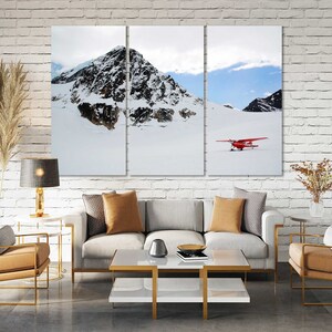 May include: A three-panel canvas print featuring a snowy mountain landscape with a red airplane flying over a snow-covered field.