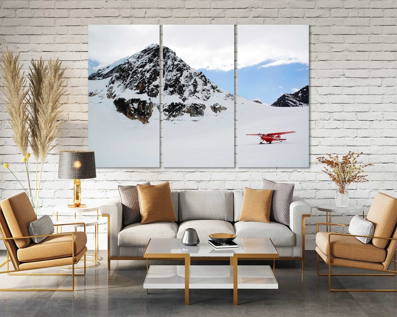 May include: A three-panel canvas print featuring a snowy mountain landscape with a red airplane flying over a snow-covered field.
