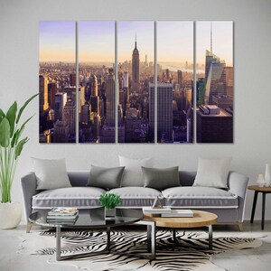 May include: A panoramic view of the New York City skyline at sunset. The image is split into five sections, showing the city from a high vantage point. The Empire State Building and the Chrysler Building are visible in the distance.