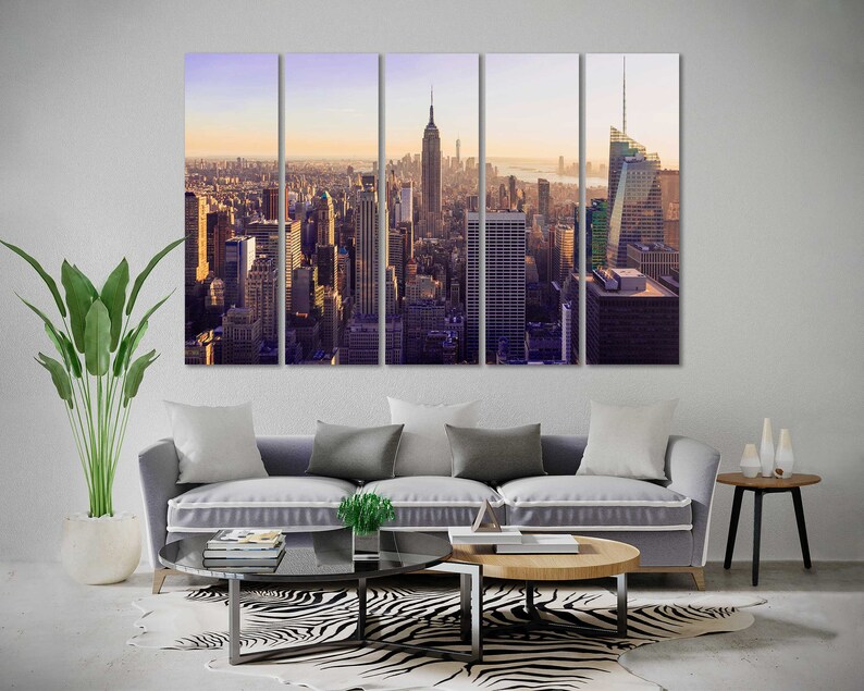 May include: A panoramic view of the New York City skyline at sunset. The image is split into five sections, showing the city from a high vantage point. The Empire State Building and the Chrysler Building are visible in the distance.
