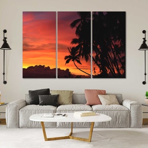 May include: A split-panel canvas print featuring a sunset over a tropical island with palm trees silhouetted against the orange and red sky.