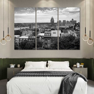 K&ouml;nnte beinhalten: Ein Schwarzwei&szlig;foto einer Skyline mit Geb&auml;uden und B&auml;umen. Das Foto ist in einem dreiteiligen Rahmen &uuml;ber einem Bett mit einer wei&szlig;en Bettdecke und einer schwarz-wei&szlig;en Tagesdecke ausgestellt.
