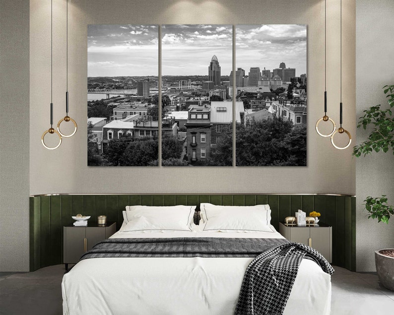 K&ouml;nnte beinhalten: Ein Schwarzwei&szlig;foto einer Skyline mit Geb&auml;uden und B&auml;umen. Das Foto ist in einem dreiteiligen Rahmen &uuml;ber einem Bett mit einer wei&szlig;en Bettdecke und einer schwarz-wei&szlig;en Tagesdecke ausgestellt.