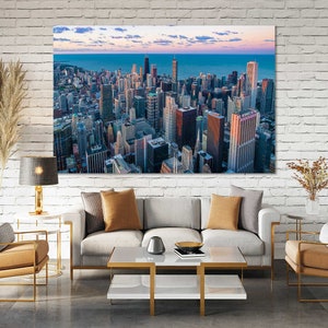 May include: A panoramic view of the Chicago skyline at sunset, with tall buildings and a blue sky with clouds. The city is reflected in the water in the distance.