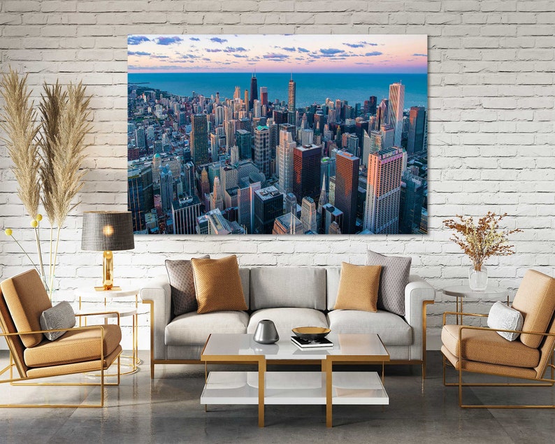 May include: A panoramic view of the Chicago skyline at sunset, with tall buildings and a blue sky with clouds. The city is reflected in the water in the distance.