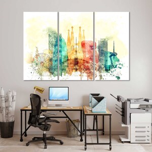 May include: A watercolor painting of a cityscape with a Ferris wheel, buildings, and a red balloon. The painting is divided into three panels and is framed in a modern office setting with a desk, chair, and printer.