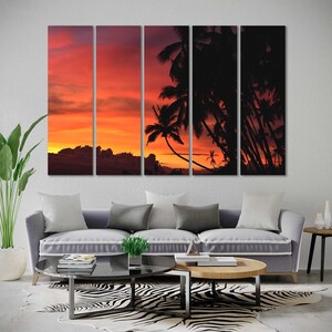 May include: A multi-panel canvas print featuring a sunset over a tropical island with palm trees silhouetted against the orange and red sky.