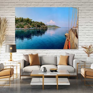May include: A photograph of a blue body of water with a green island in the background. The photo was taken from a boat, and the side of the boat is visible on the right side of the image.