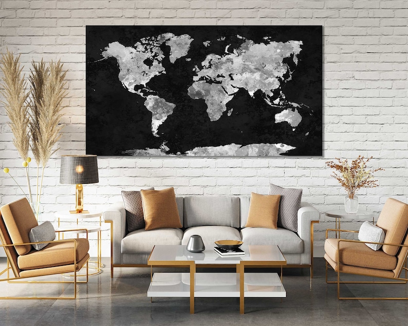 May include: A living room interior with a white brick wall, a grey sofa with two tan cushions, a coffee table with a book and a bowl, a black and white world map print hanging on the wall, and two tan armchairs with gold frames.