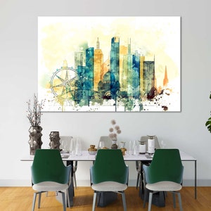 May include: A watercolor painting of a city skyline with a Ferris wheel in the foreground. The buildings are painted in shades of blue, green, and yellow, and the sky is a light yellow. The painting is framed and hanging on a white wall.