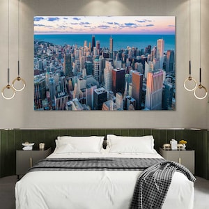 May include: An aerial view of a city skyline with tall buildings and a body of water in the distance. The city is bathed in the warm glow of the setting sun.