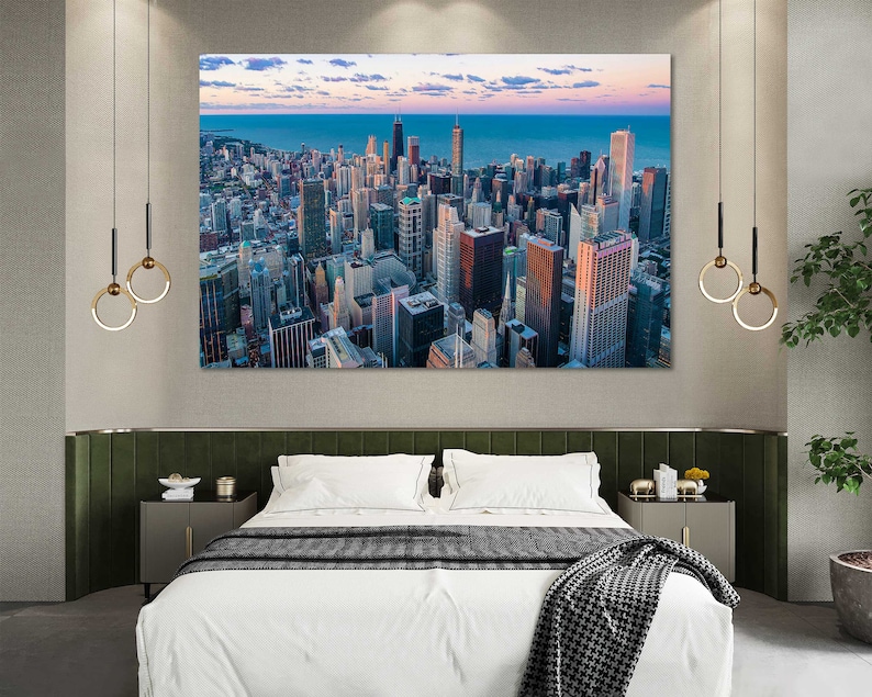 May include: An aerial view of a city skyline with tall buildings and a body of water in the distance. The city is bathed in the warm glow of the setting sun.