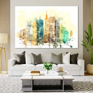 May include: A watercolor painting of a cityscape with tall buildings and a bridge. The buildings are painted in shades of yellow, orange, brown, and green. The bridge is painted in a light brown color. The painting has a white background with splashes of watercolor paint.