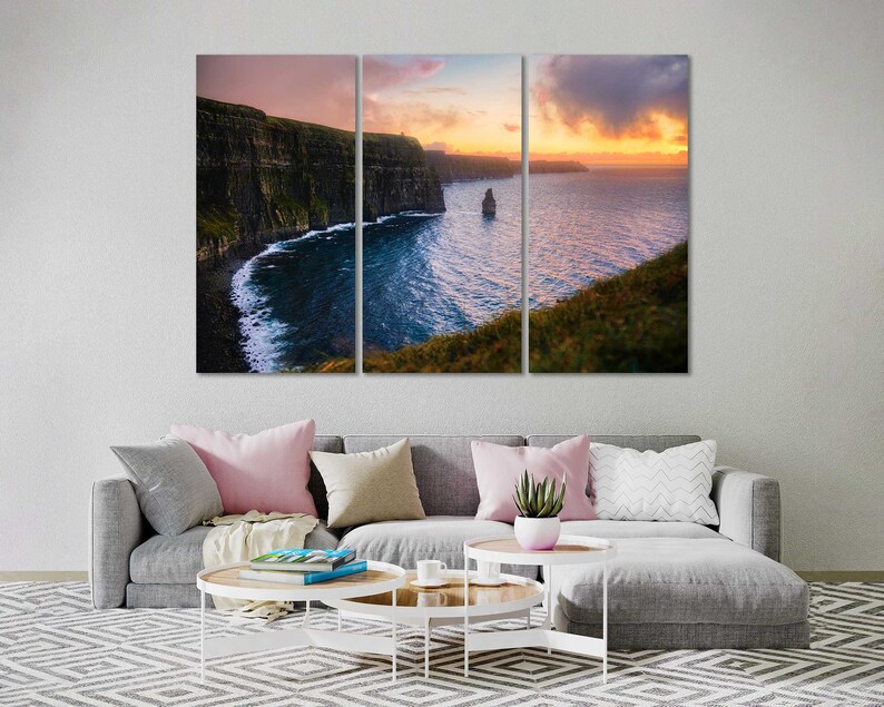 Puede incluir: Una vista panor&aacute;mica de los Acantilados de Moher en Irlanda al atardecer. Los acantilados son un hito natural dram&aacute;tico con una costa accidentada y un oc&eacute;ano azul profundo. El cielo es una mezcla vibrante de tonos rosados, naranjas y morados, creando un tel&oacute;n de fondo impresionante para los acantilados.