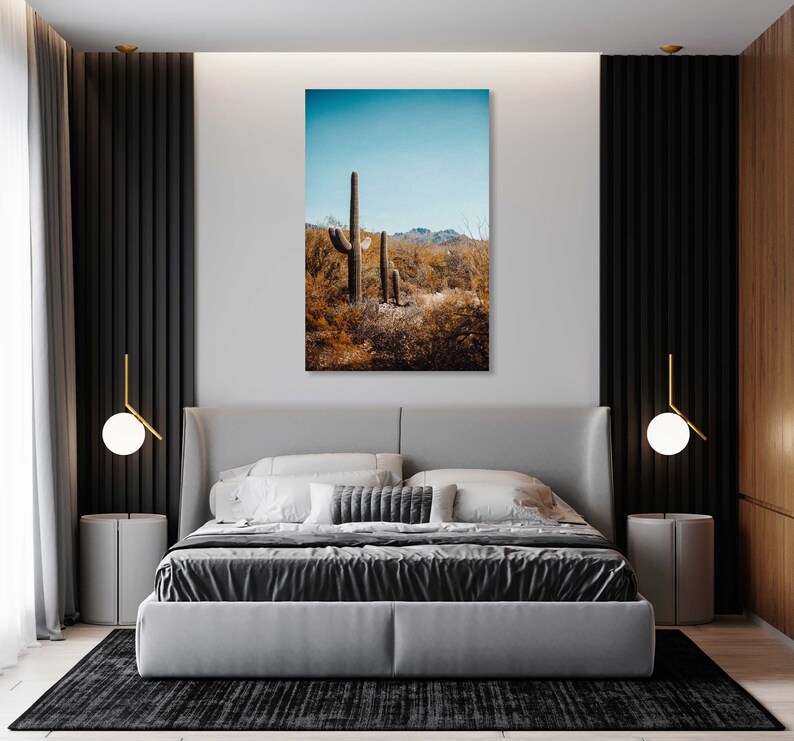 May include: A photograph of a desert landscape with tall cacti in the foreground. The sky is blue and the ground is covered in brown brush.
