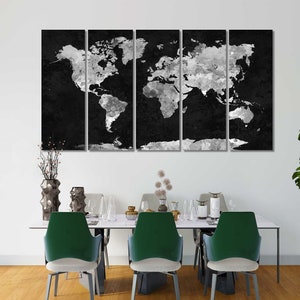 May include: A black and white world map canvas print, divided into three panels, hanging on a white wall above a dining table with green chairs.