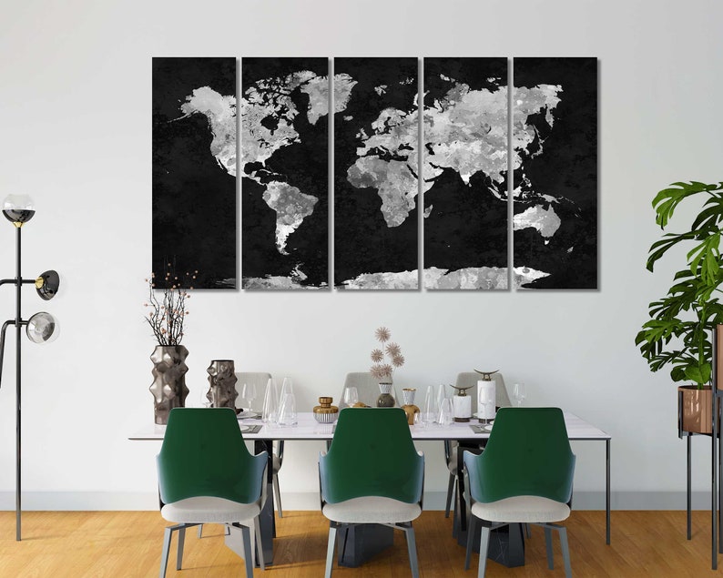 May include: A black and white world map canvas print, divided into three panels, hanging on a white wall above a dining table with green chairs.