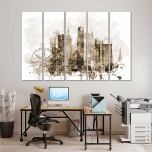 May include: A sepia-toned canvas print of a city skyline with a Ferris wheel in the foreground. The print is divided into five panels, each with a different section of the city. The print is hanging on a white wall above a desk with a computer, chair, and printer.