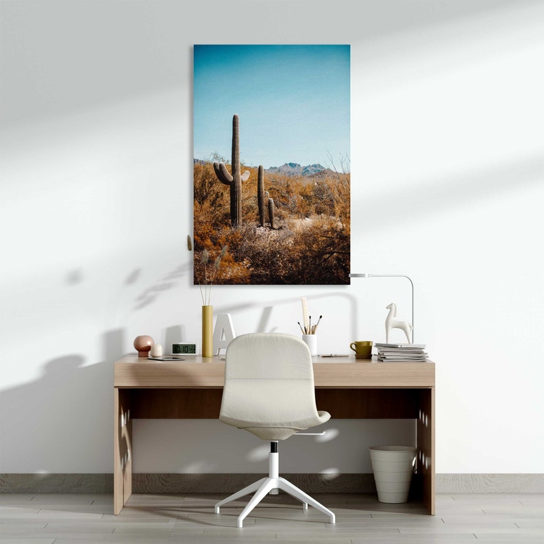May include: A photograph of a desert landscape with three tall cacti in the foreground. The sky is blue and the ground is covered in brown brush.