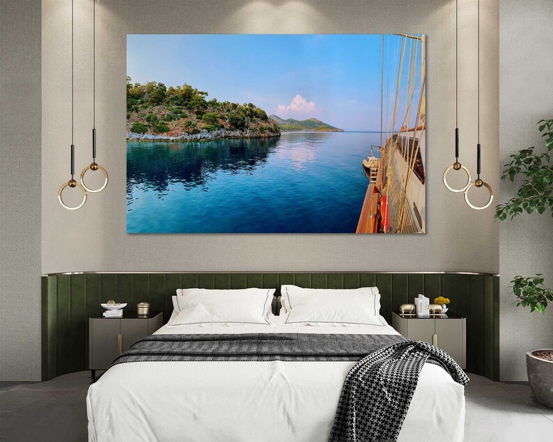 May include: A panoramic photograph of a blue body of water with a green island in the distance. The water is calm and reflects the sky. A wooden boat is docked on the right side of the image.