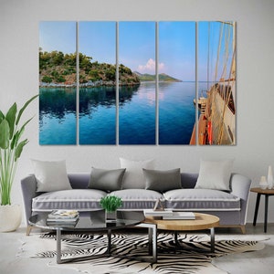 May include: A panoramic view of a blue body of water with a green island in the background. A white sailboat is docked in the foreground. The image is split into five sections.