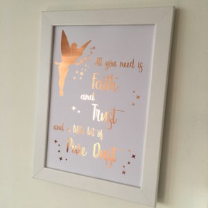 May include: A white framed print with a gold foil Tinkerbell silhouette and the quote "All you need is faith and trust and a little bit of pixie dust".