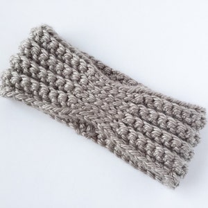 May include: A grey crocheted headband. The headband is made with a thick yarn and has a simple, textured design.