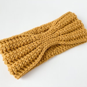 May include: A mustard yellow crocheted headband with a twisted design.