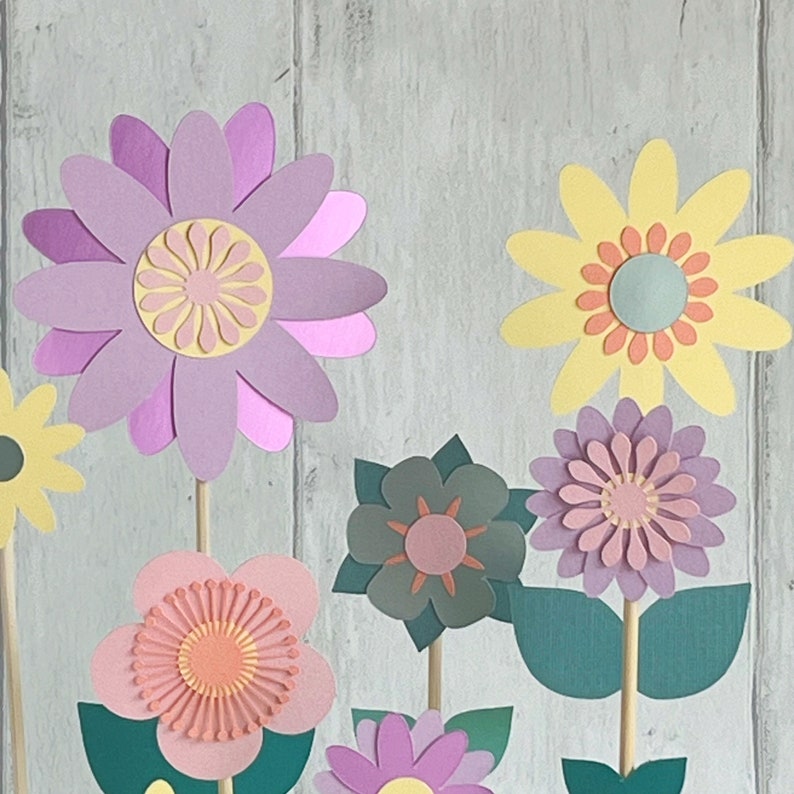 Pu&ograve; includere: Un set di fiori di carta in varie tonalit&agrave; di rosa, viola e giallo. I fiori sono sovrapposti e hanno un effetto 3D. Sono disposti in un bouquet e sarebbero un'ottima aggiunta a un arredamento per la casa o un progetto artigianale.