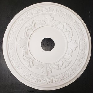 May include: White ceiling medallion with a decorative floral design. The medallion has a round shape and a hole in the center.