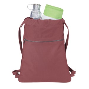 Puede incluir: Una mochila de cord&oacute;n de color marr&oacute;n rojizo con un bolsillo frontal con cremallera. La mochila est&aacute; llena con una botella de agua transparente y una toalla verde.