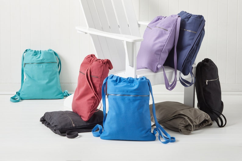 Puede incluir: Un conjunto de nueve mochilas de cord&oacute;n en varios colores, incluyendo turquesa, rojo, azul, morado, negro y gris. Las mochilas tienen un bolsillo con cremallera en la parte delantera y est&aacute;n hechas de un material similar al lienzo.