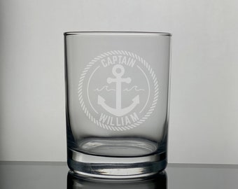 May include: A clear glass tumbler with an etched design of an anchor, rope, and the text "Captain William".