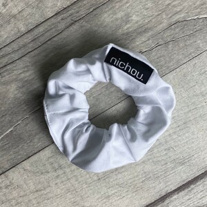 May include: White scrunchie with a black label that says "nichou."