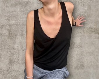 May include: A black sleeveless tank top with a V-neckline. The tank top is made of a soft, stretchy fabric and has a relaxed fit.
