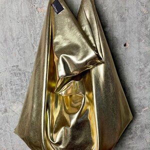 Pode incluir: Uma bolsa tote dourada met&aacute;lica com uma etiqueta preta que diz "nichou".