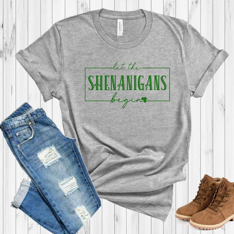 May include: A gray t-shirt with the text "Let the Shenanigans Begin" in green lettering with a shamrock.