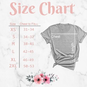 May include: Size chart for a t-shirt with measurements in inches for chest to fit. The chart shows sizes XS, S, M, L, XL, and 2XL. The chart is on a white marble background with a gray t-shirt on top.